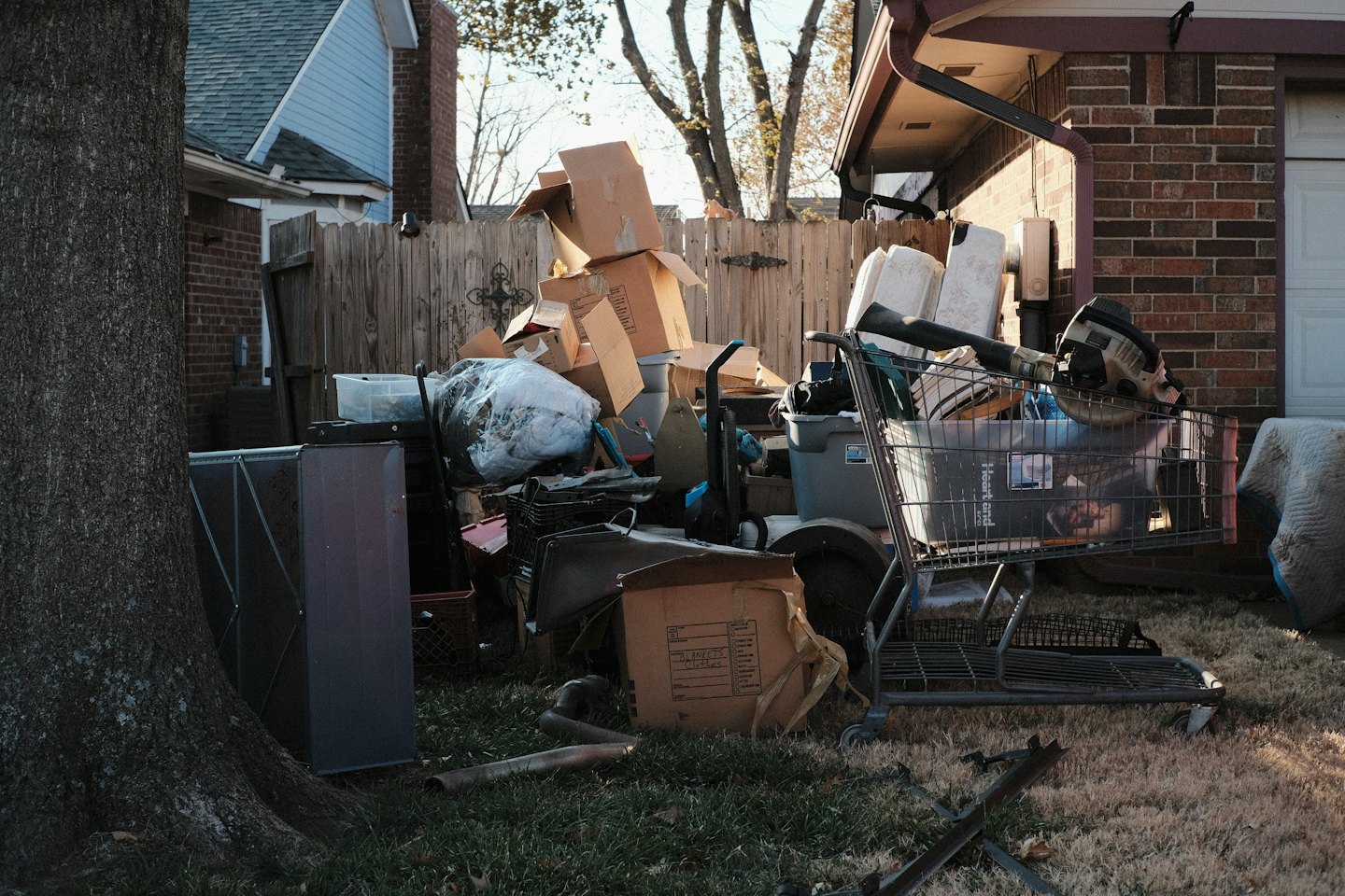 Cardboard boxes and discarded items clutter a residential backyard.